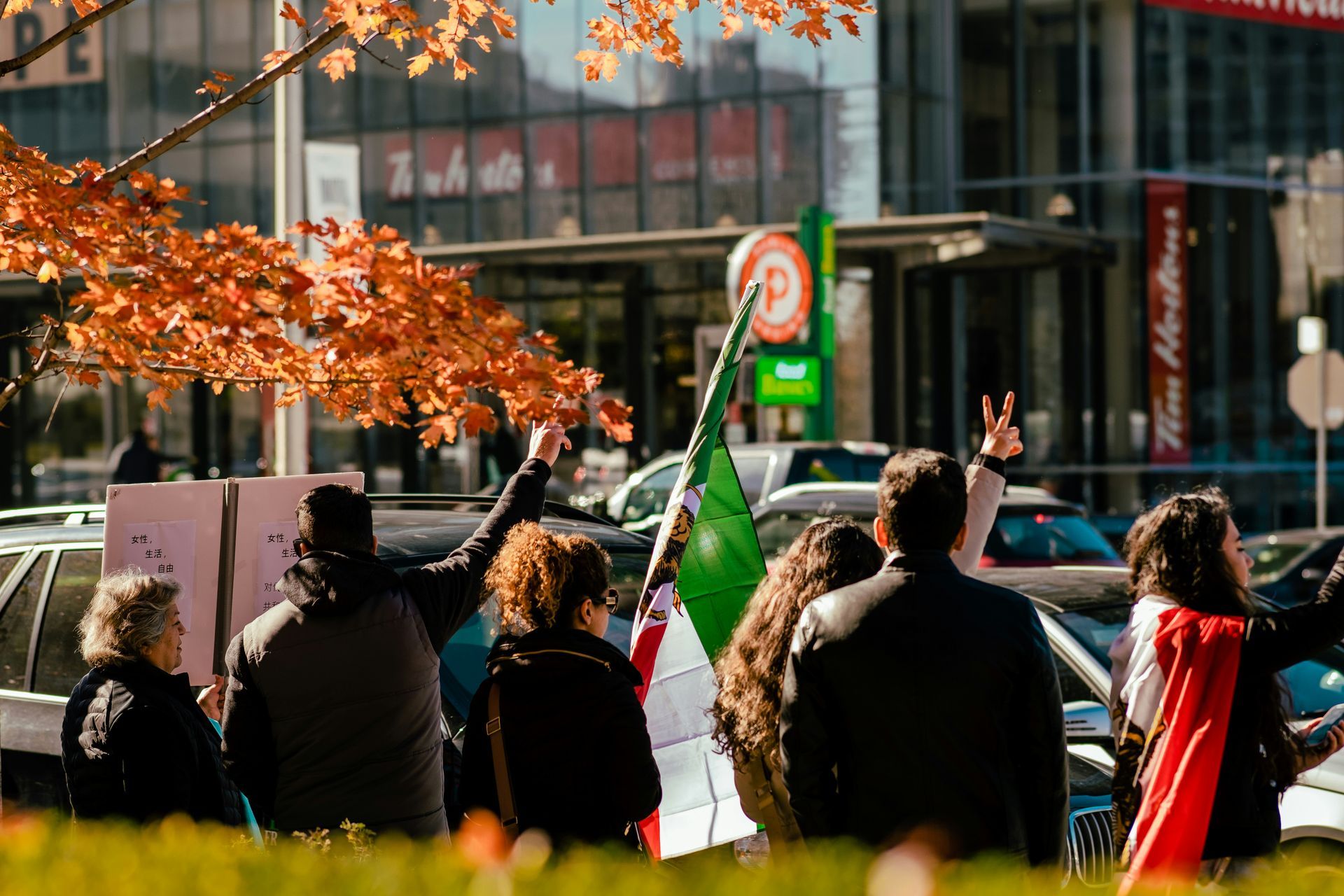 A group of people are standing in front of a building holding signs and flags.