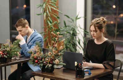 two people working at a desk with Christmas decorations on desk