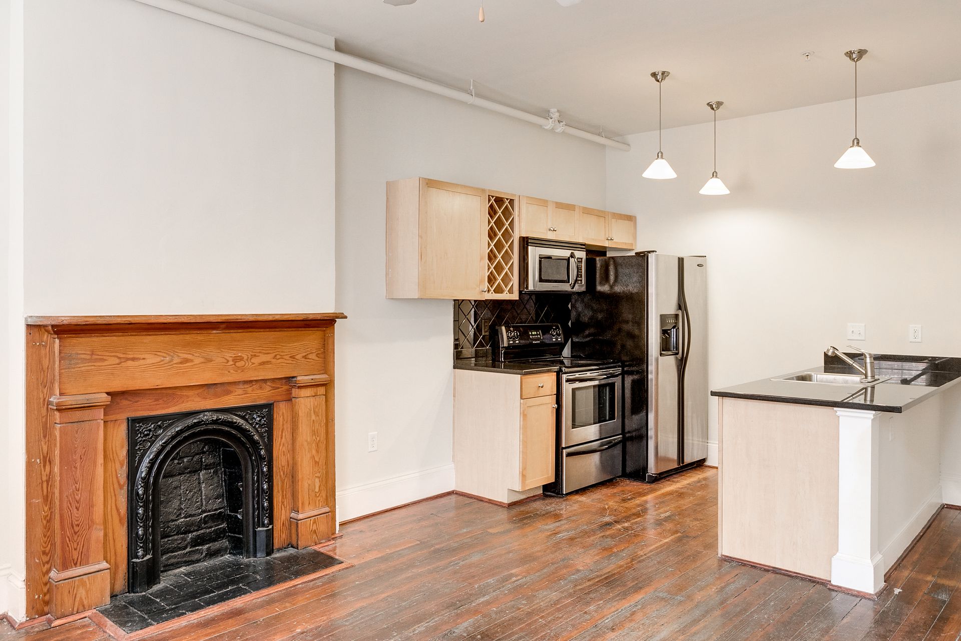 Interior of a modern kitchen with stainless steel appliances and fireplace with wooden mantel.