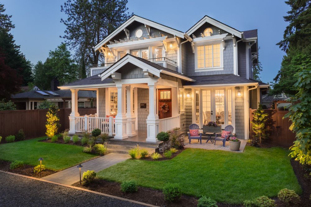 A large house with a large porch is lit up at night.