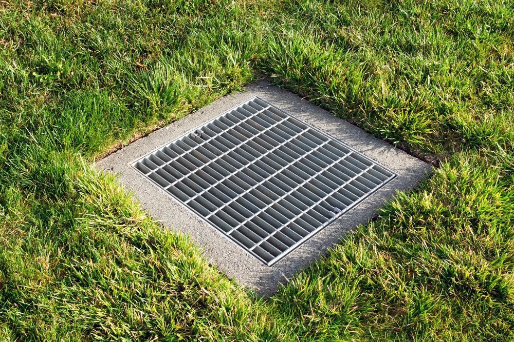 A metal grate is sitting in the middle of a lush green field.