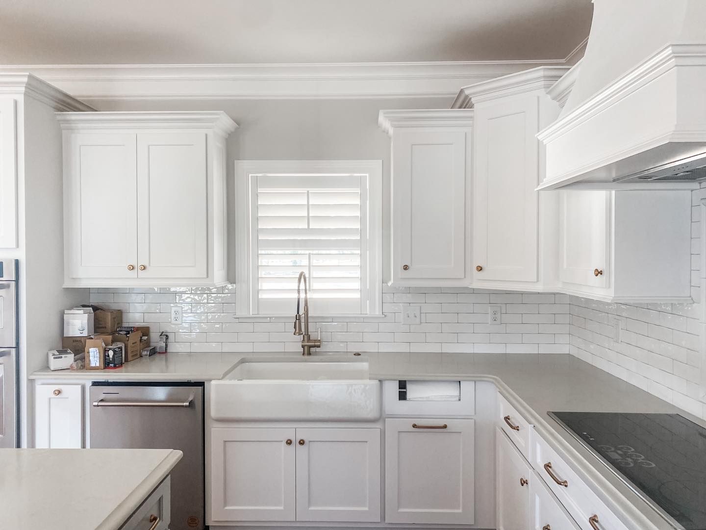 White kitchen with cabinets, a farmhouse sink, and a window with shutters.