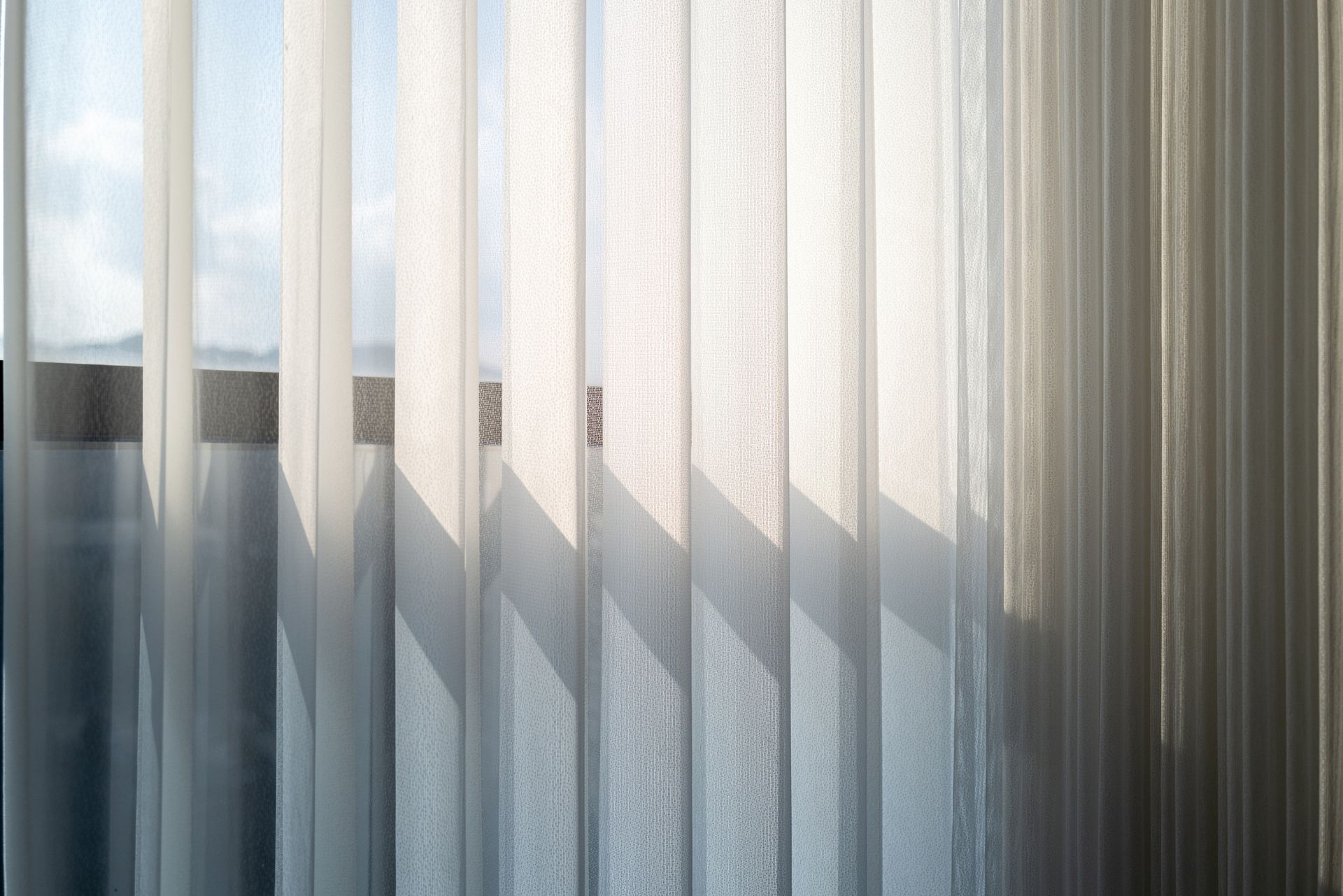 A general interior view of open blinds covering a window with bright sunlight.