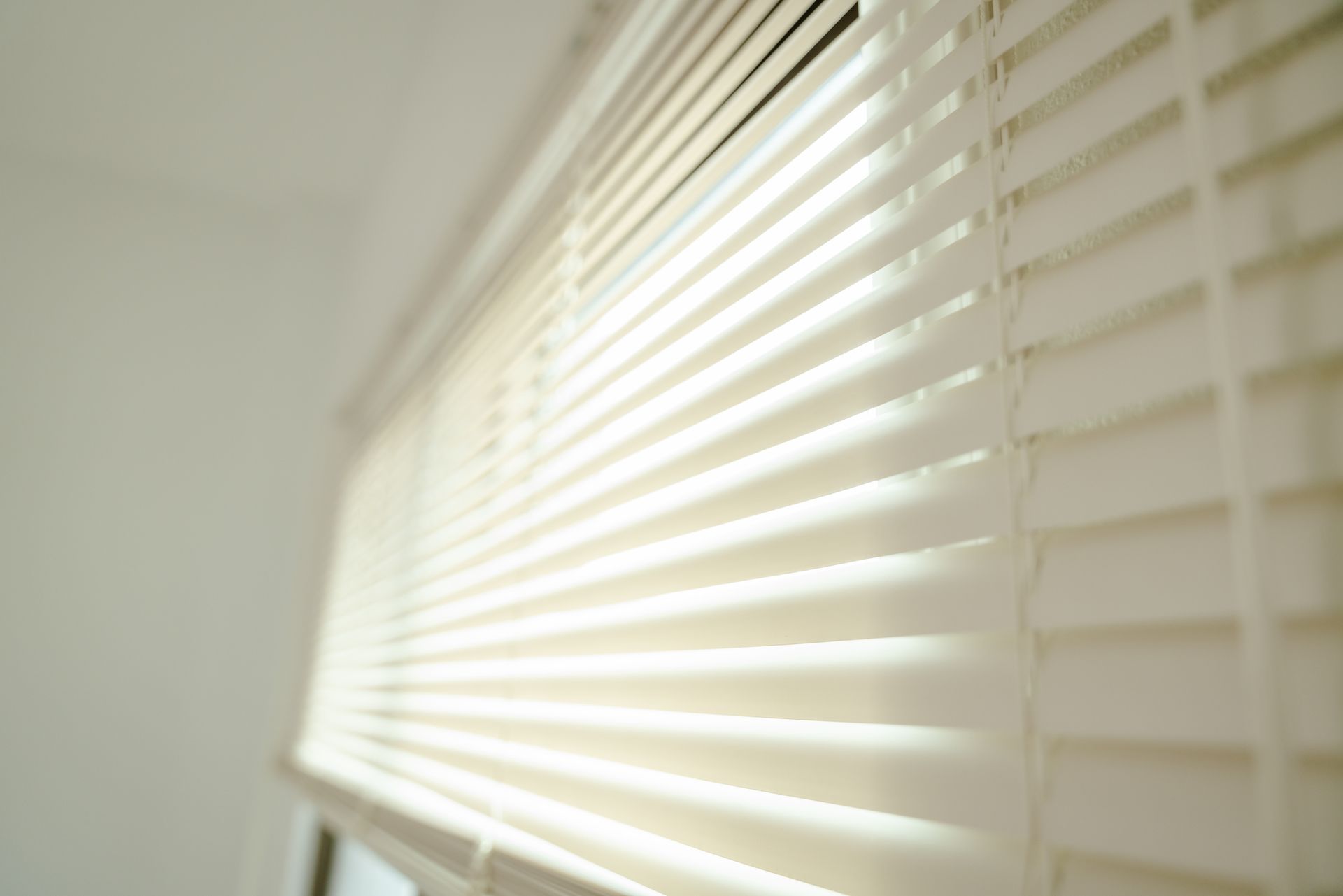 Close-up of open blinds with sunlight casting crisp shadows in a bright room.