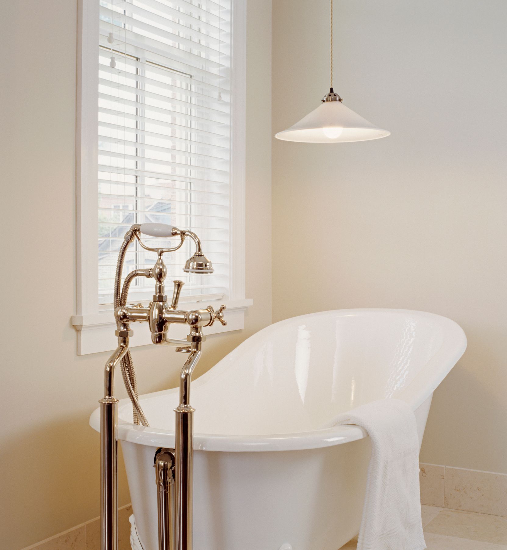 Slipper bathtub beside a large window with custom blinds for privacy.