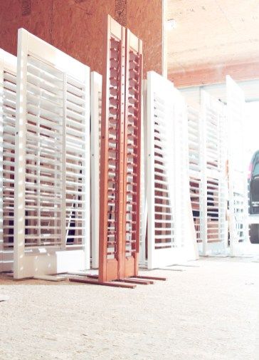 White and brown shutters lined up against a wall.