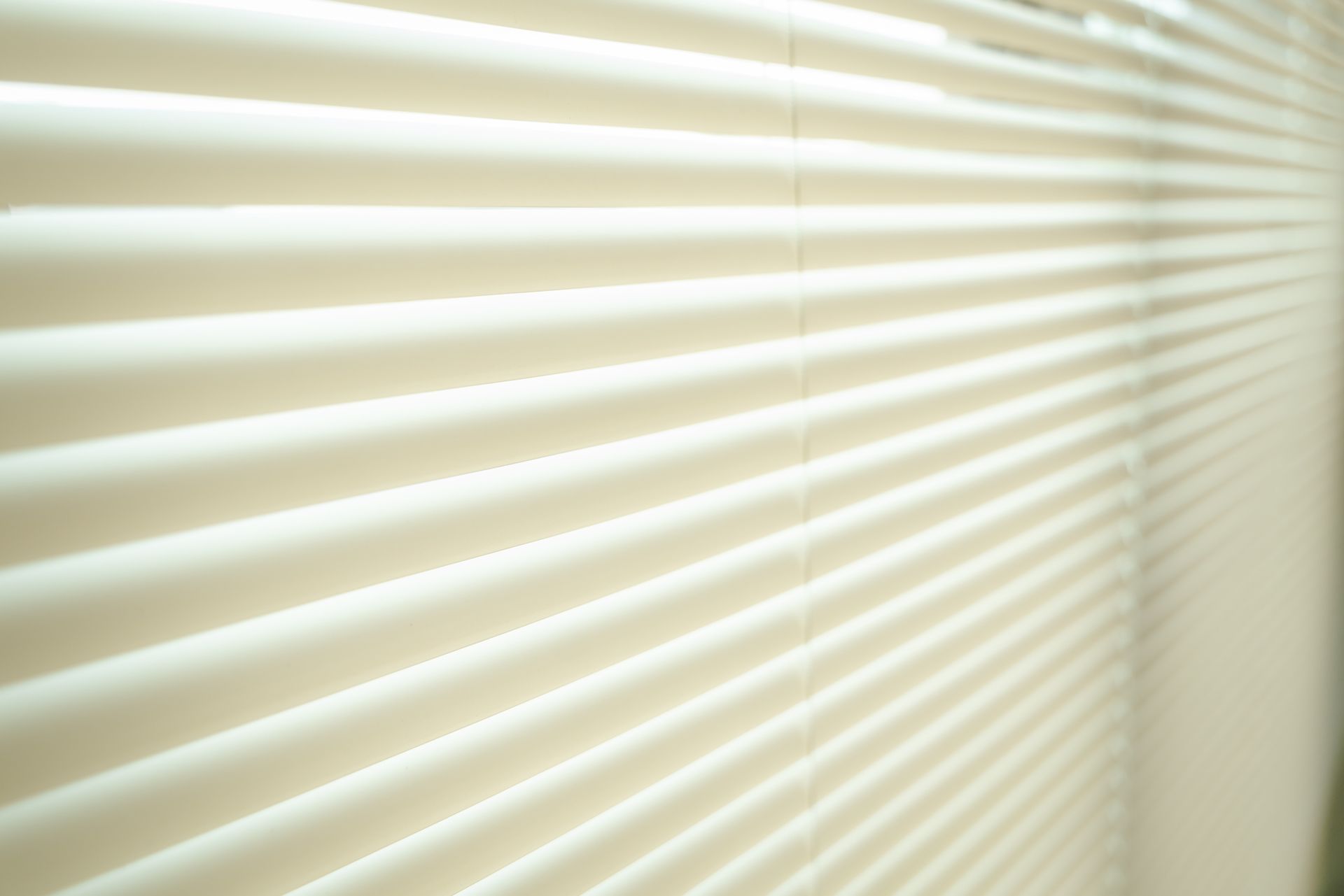 Close-up of partially open blinds in a bright room.