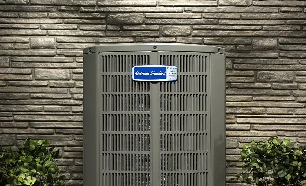 An air conditioner is sitting on the side of a brick building.