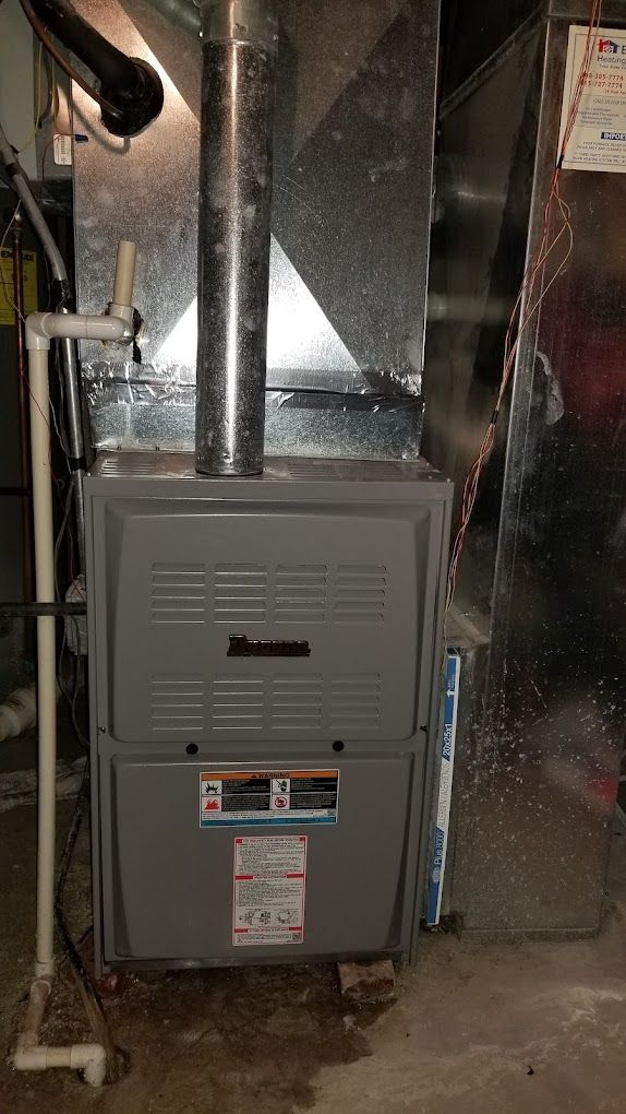 A furnace is sitting in a basement next to a wall.