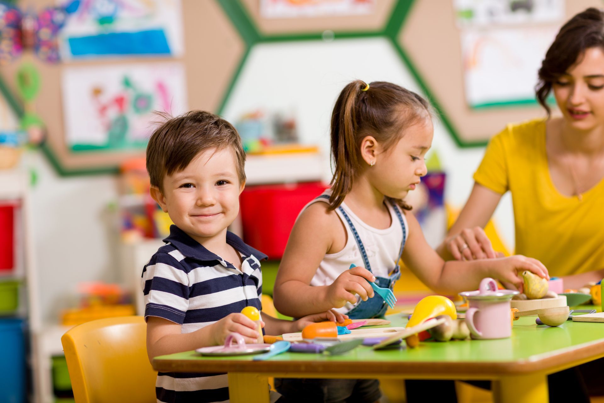 A Group of Children Are Sitting at a Table in a Classroom Playing With Toy