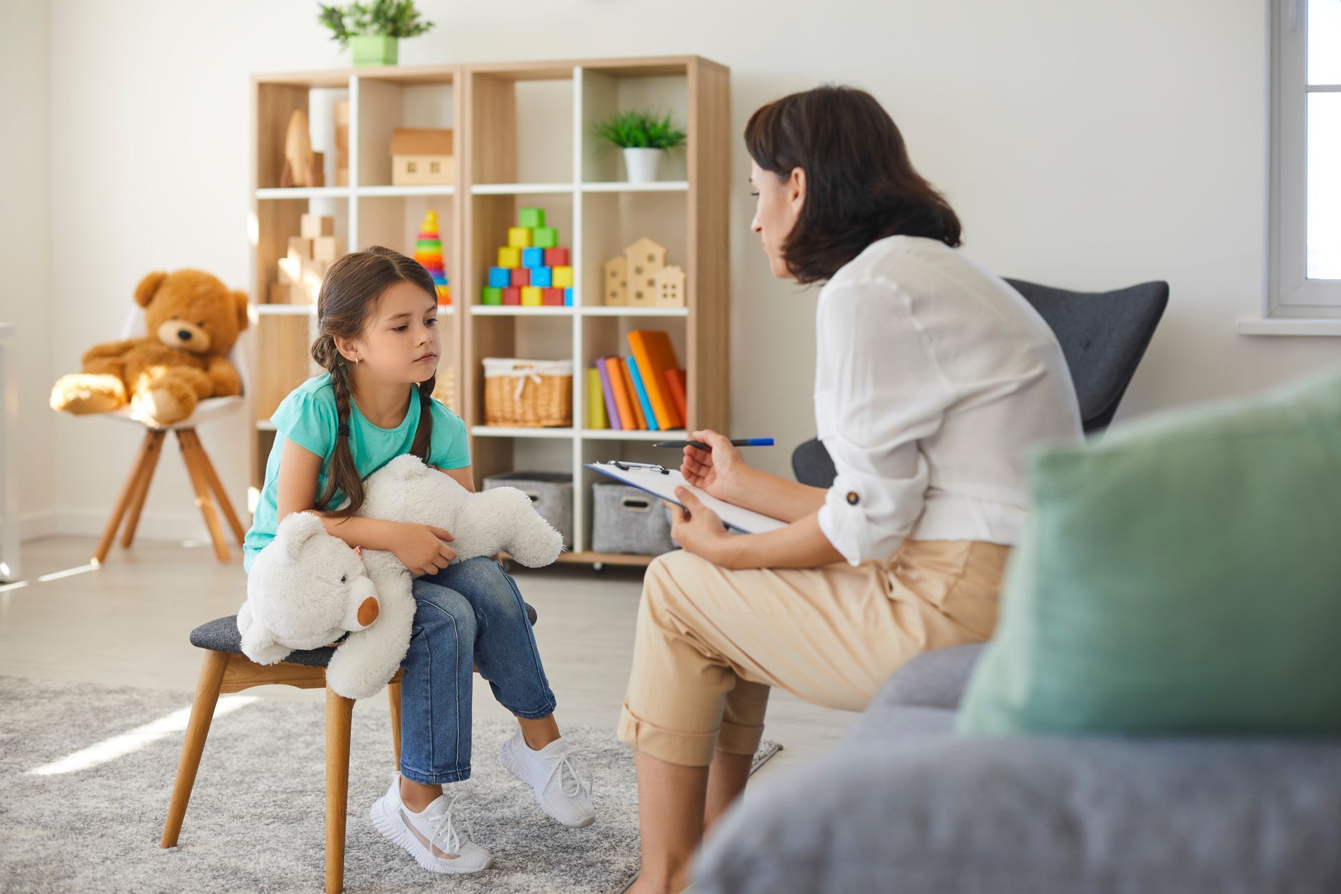 A Woman is Sitting at a Table Talking to a Little Boy