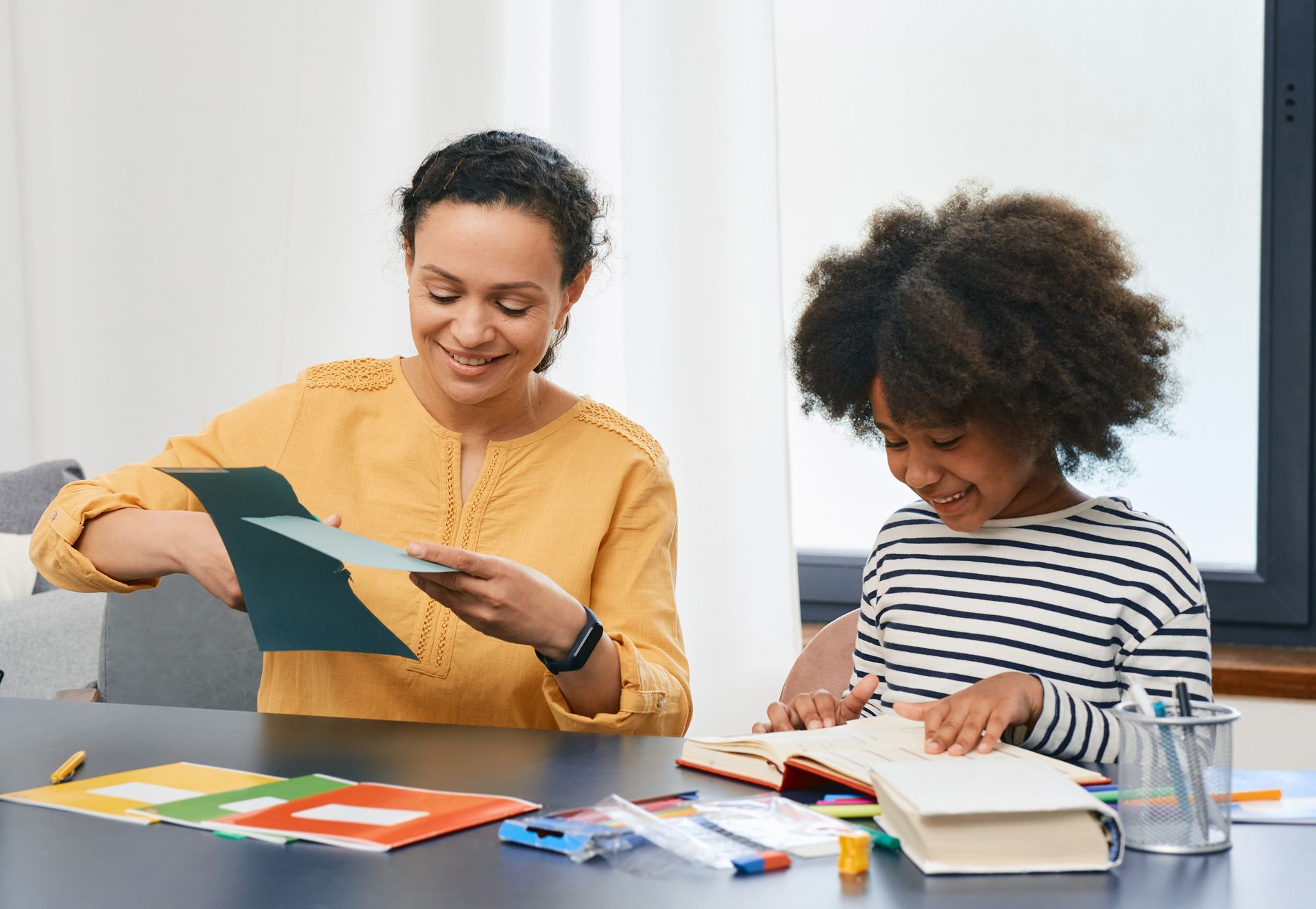 A Woman is Helping a Little Girl With Her Homework at a Table