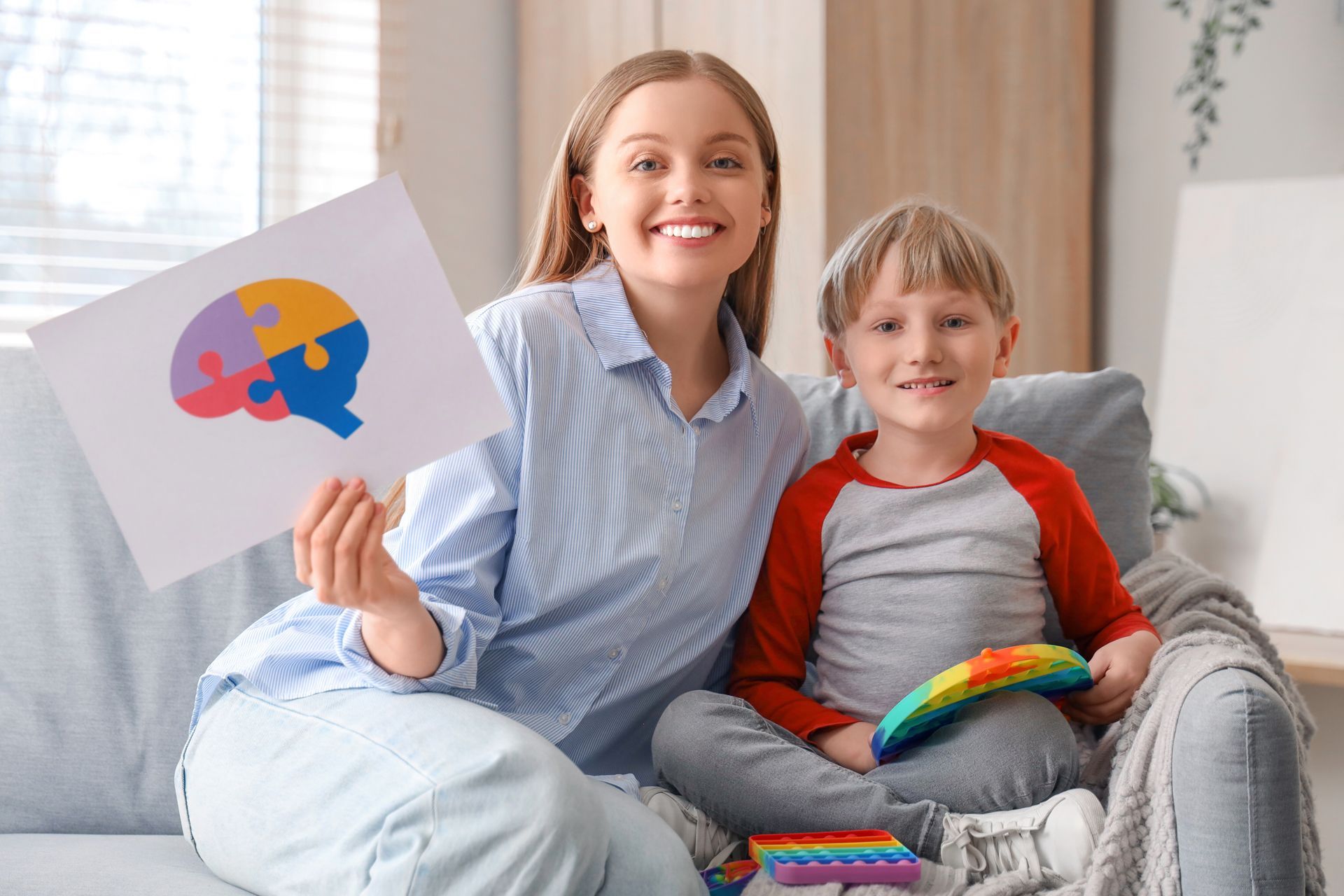 A Woman and a Boy Are Sitting on a Couch Holding a Piece of Paper With a Brain on It