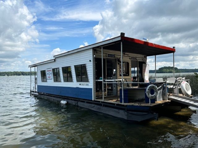 A blue and white boat is floating on top of a lake.