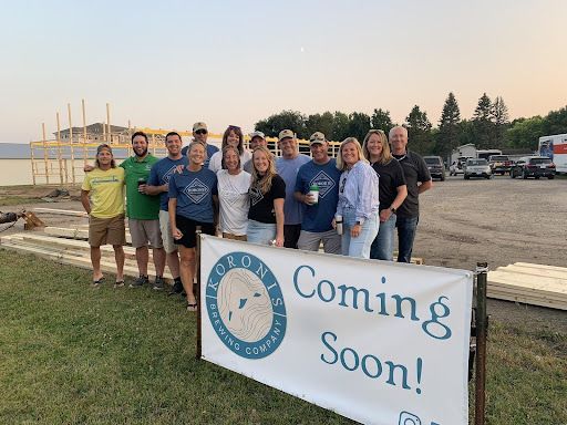 A group of people are standing in front of a coming soon sign.
