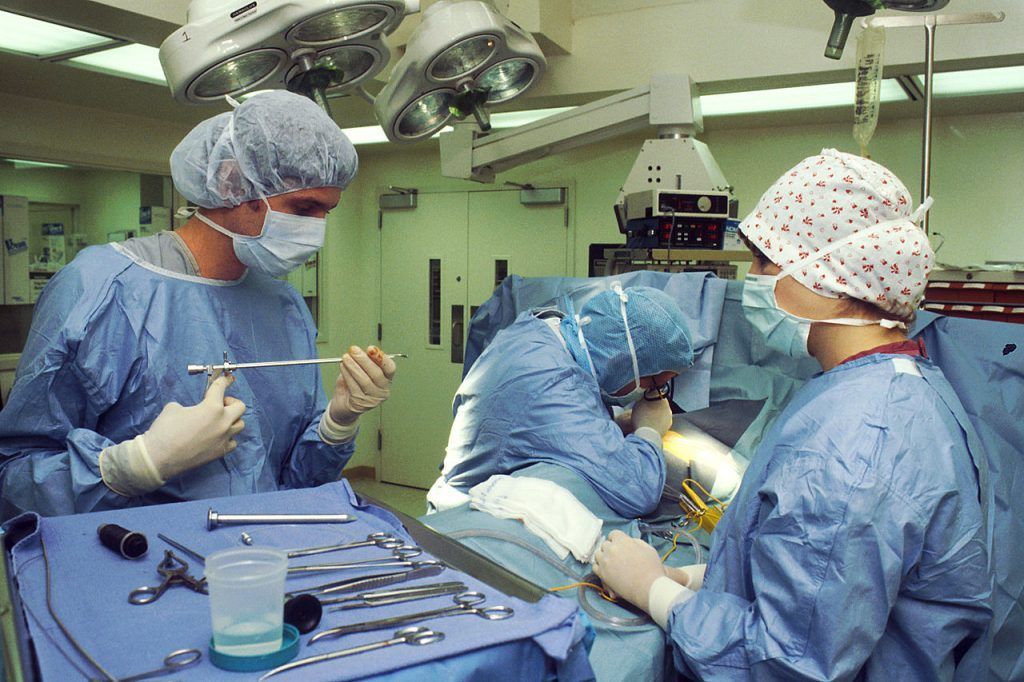 A group of surgeons are operating on a patient in an operating room