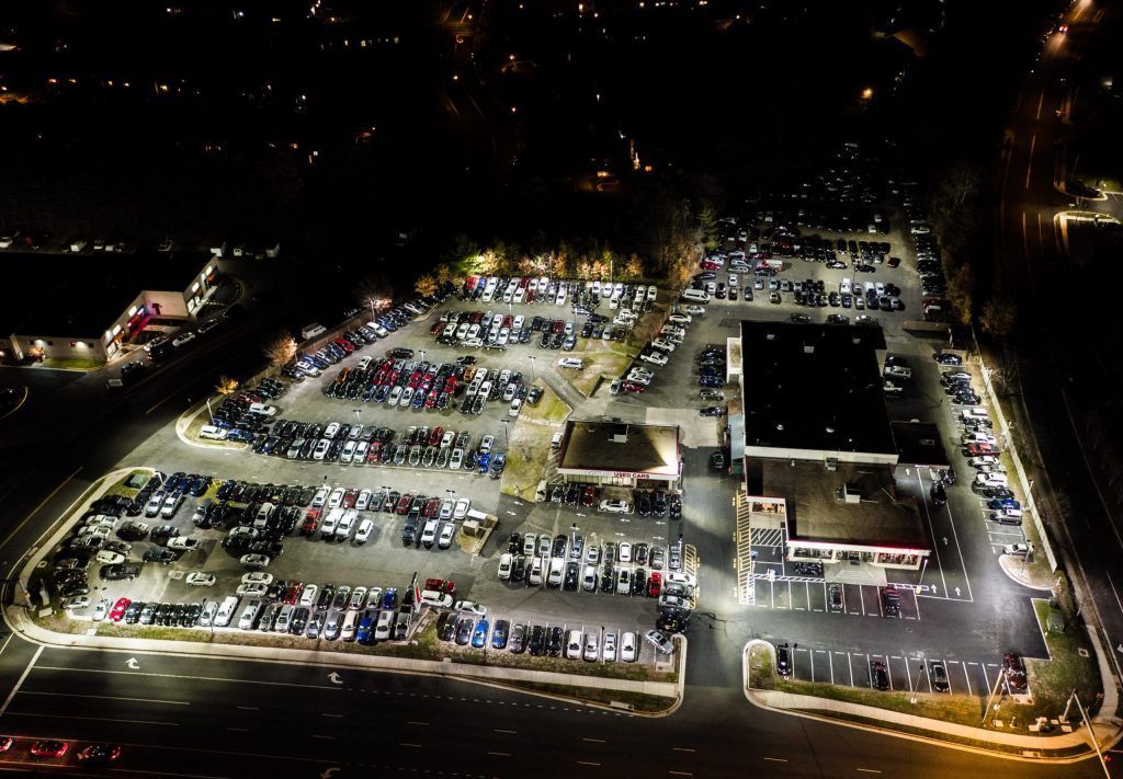 An aerial view of a parking lot at night filled with cars.