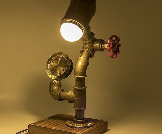 A lamp made out of pipes and a clock on a wooden base.