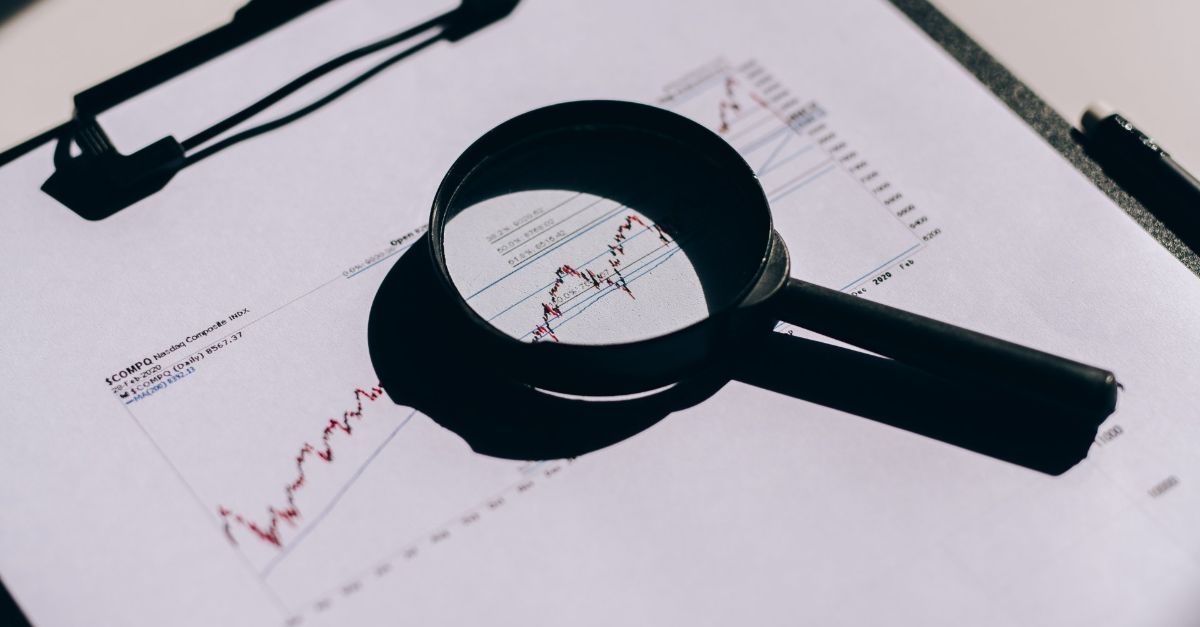 A magnifying glass is sitting on top of a clipboard with a graph on it.