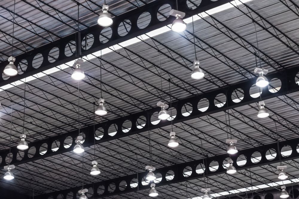 Bright overhead lights hang from a metal ceiling with circular cutouts.