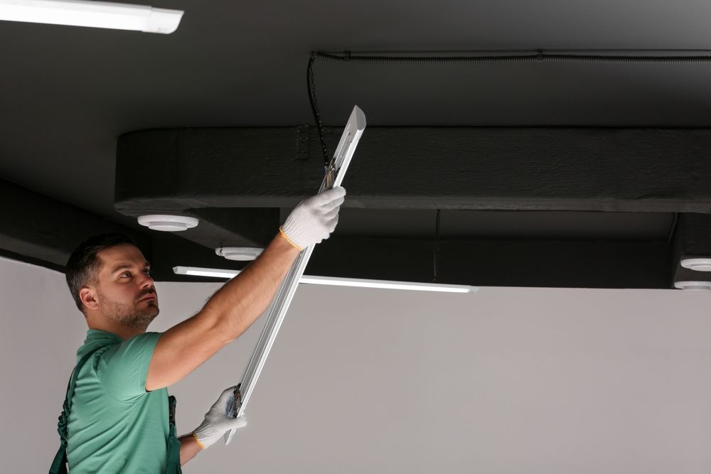 Lighting certified electrician installing new LED lighting in an office space to help boost employee productivity