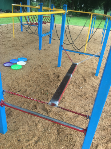 A blue and yellow playground with frisbees in the sand