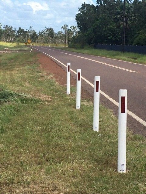 A row of white poles on the side of a road