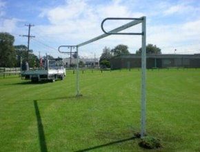 A truck is parked in a grassy field next to a soccer goal.