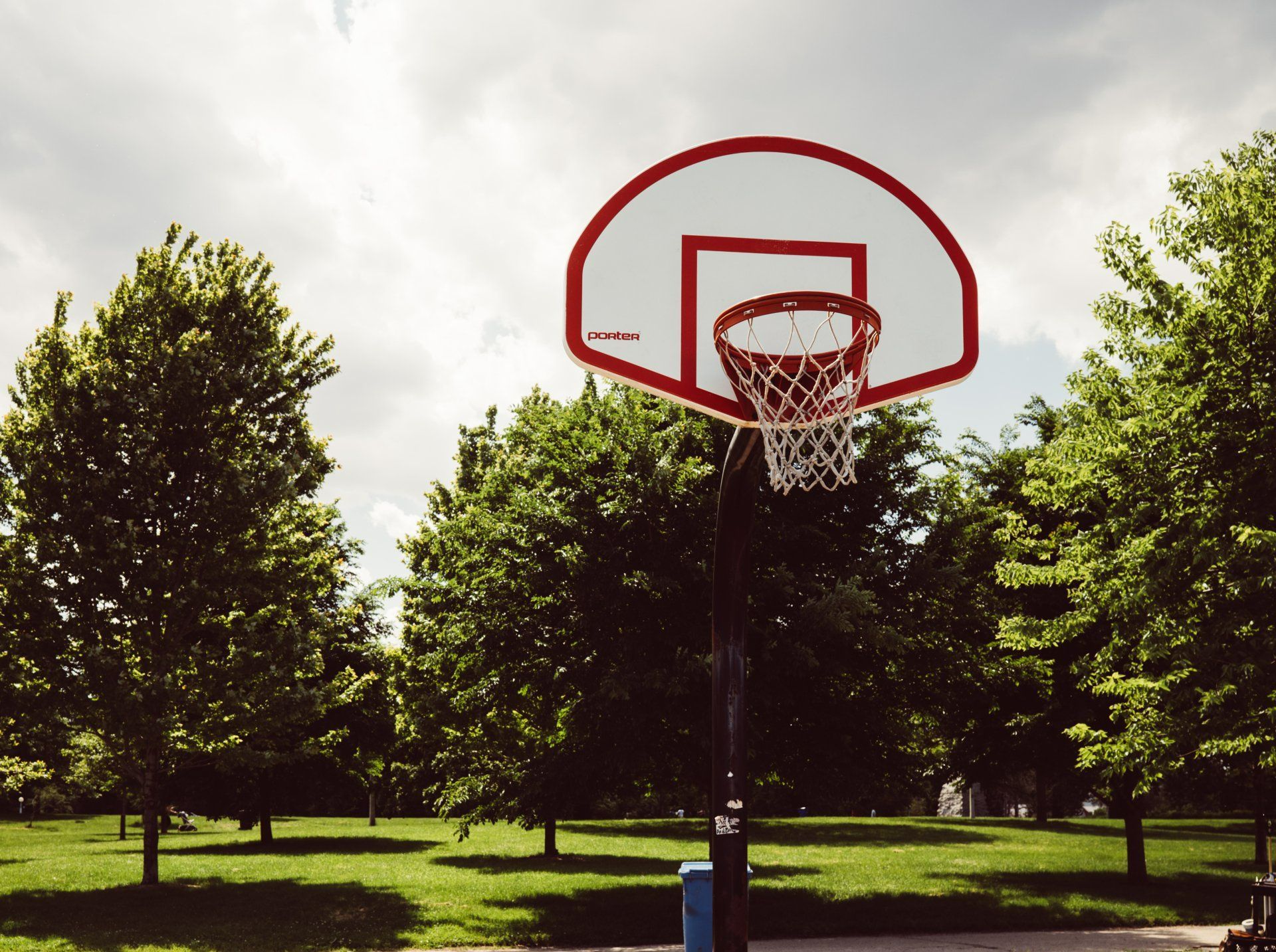 A basketball hoop in a park with trees in the background