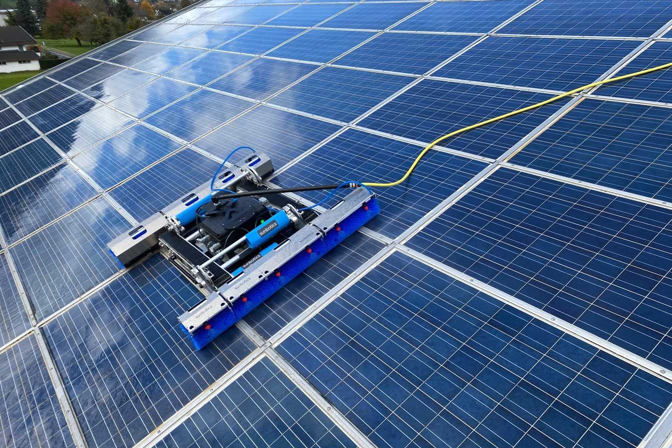 Reinigungsroboter für Solarmodule mit blauen Bürsten auf einer Solarmodulgruppe.