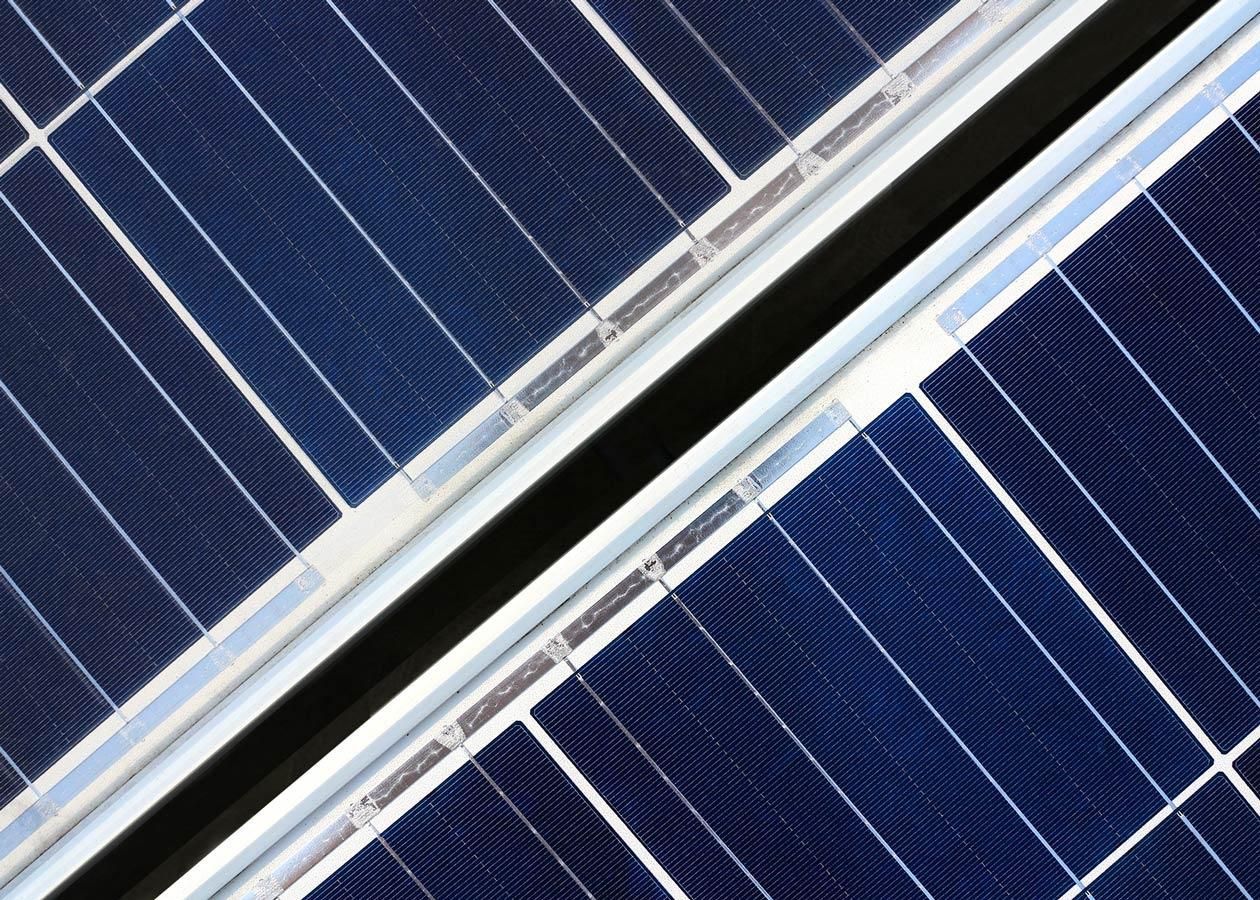 Nahaufnahme von blauen Solarzellen in diagonaler Anordnung, die die Zellen und die Tragstrukturen zeigt.