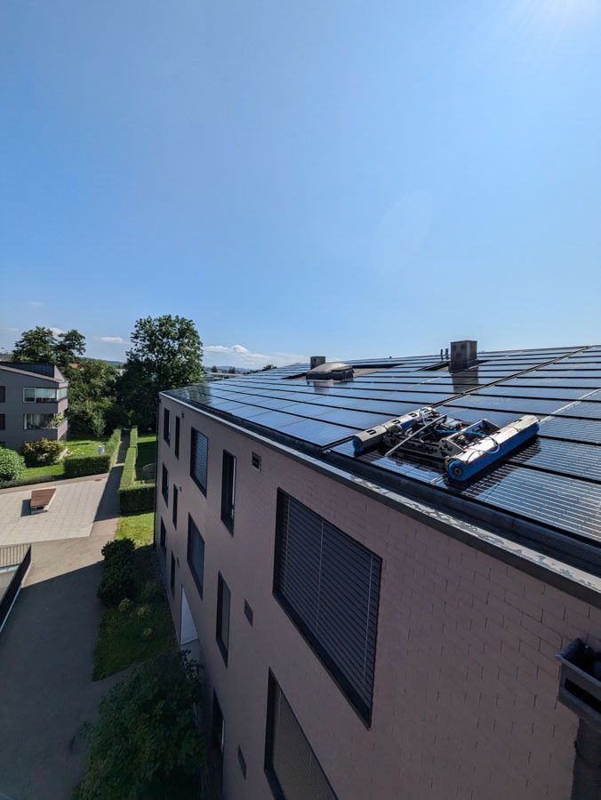 Solarmodule auf einem Gebäudedach unter strahlend blauem Himmel.