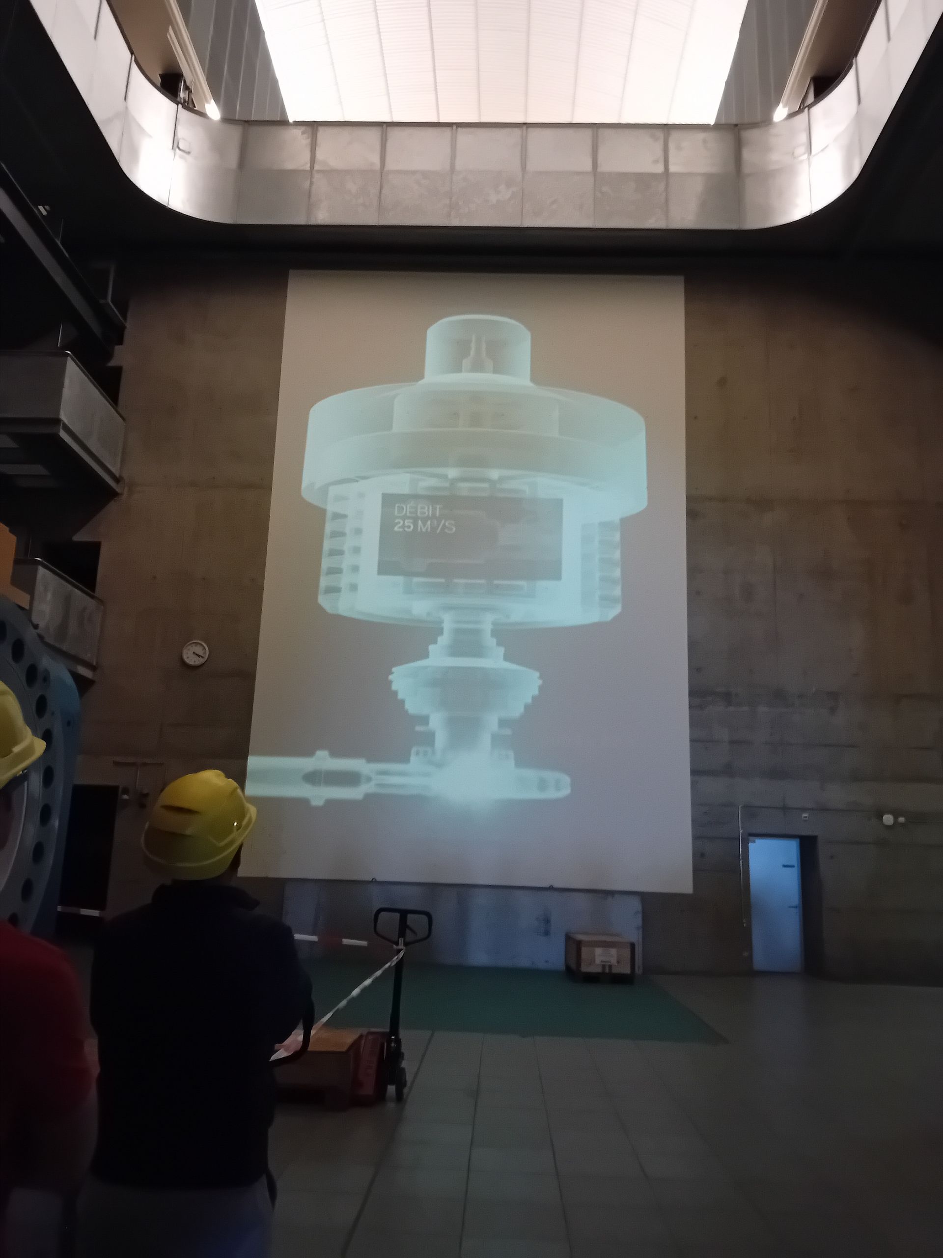 Un homme portant un casque de sécurité se tient devant un grand écran de projection