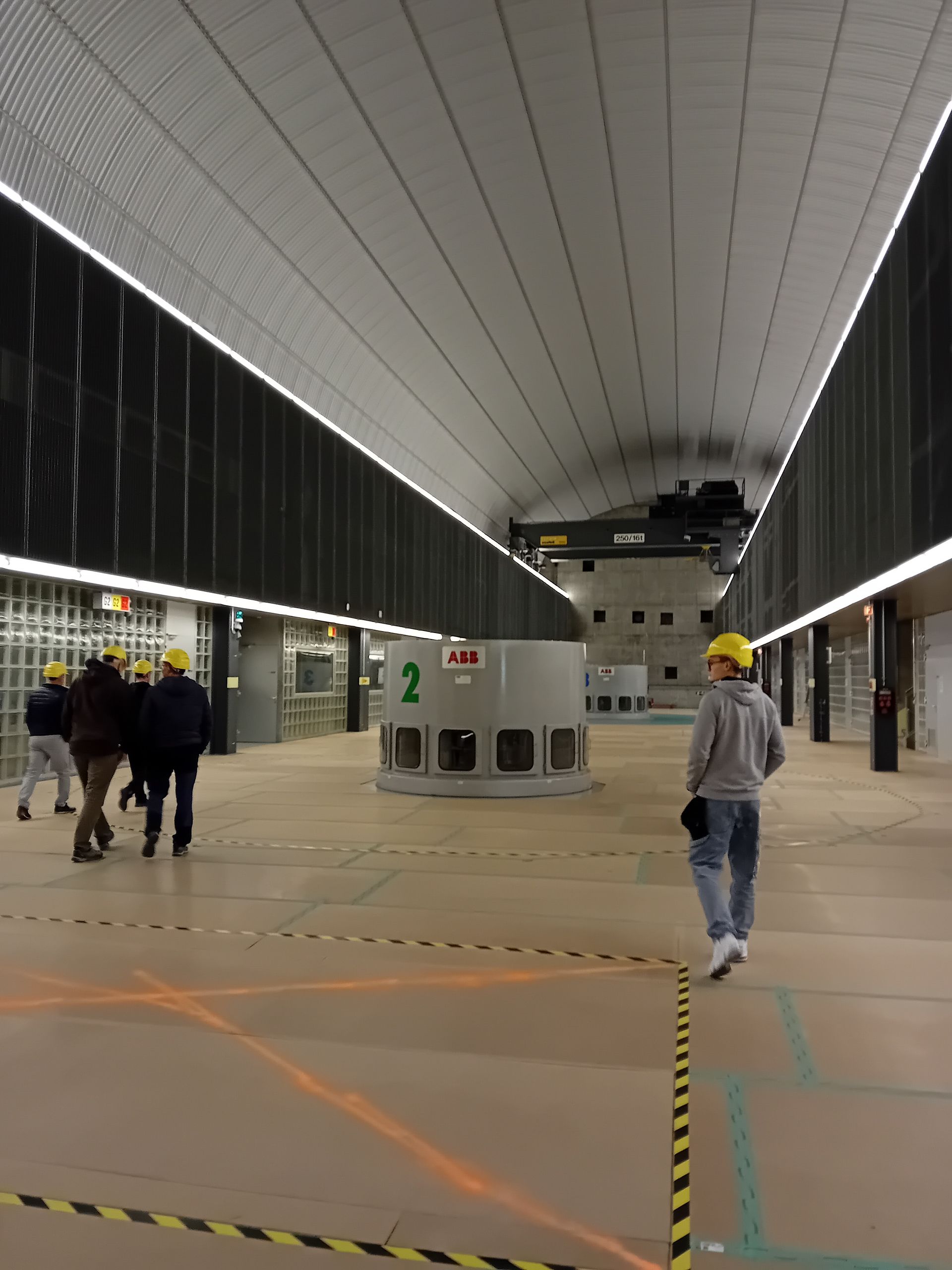 Un groupe de personnes marche dans une grande pièce avec une machine avec le numéro 2 dessus.