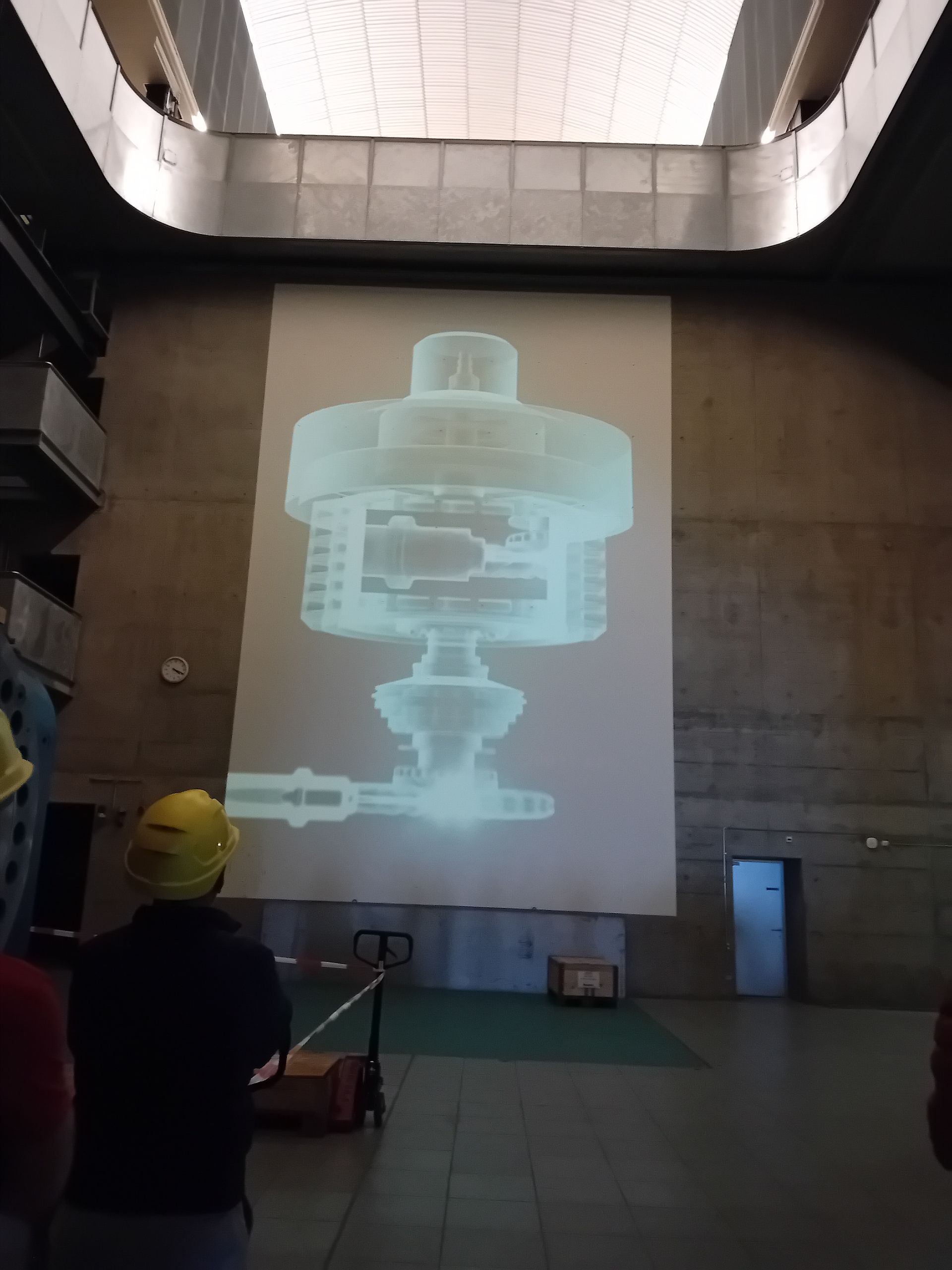 Un homme portant un casque de sécurité se tient devant un grand écran de projection