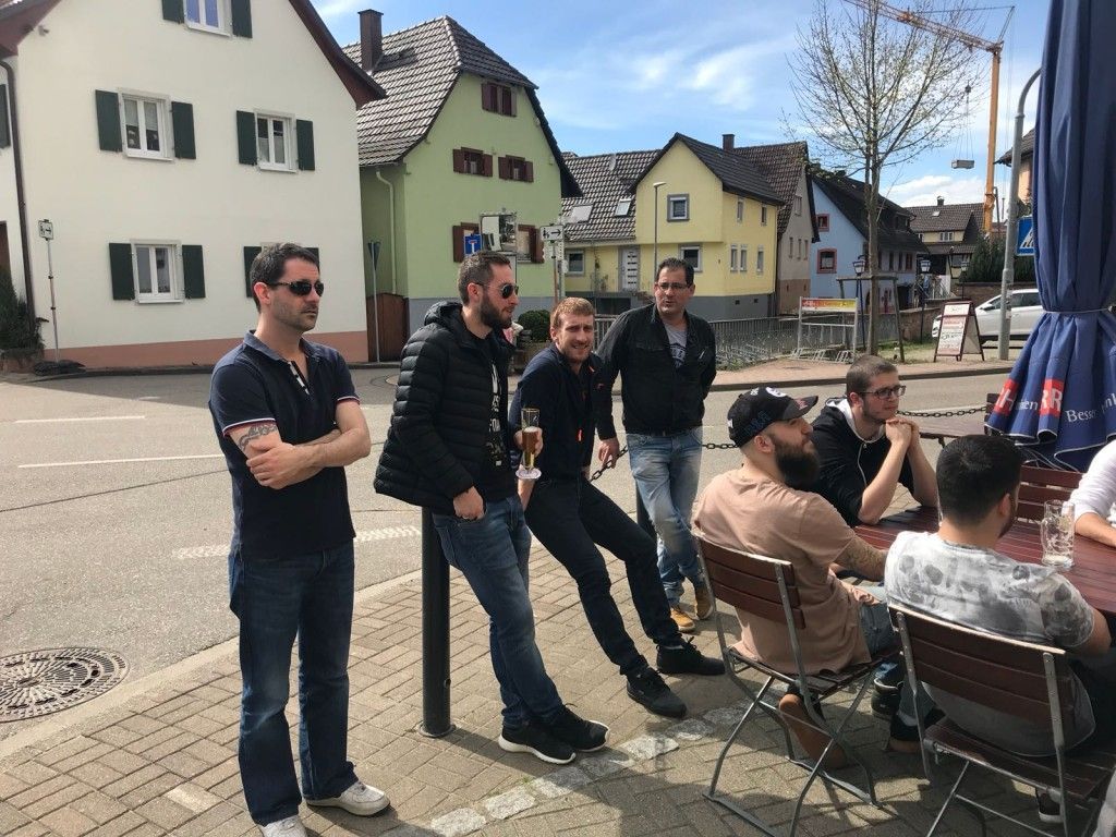 Un groupe d'hommes sont debout et assis sur un trottoir.