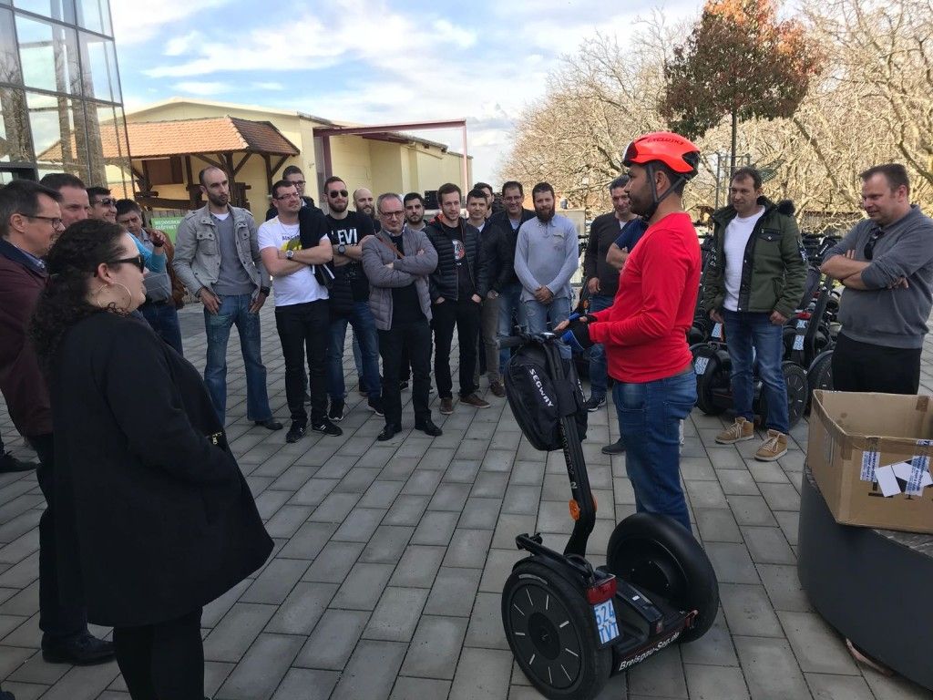 Un groupe de personnes se tient autour d'un homme sur un segway.
