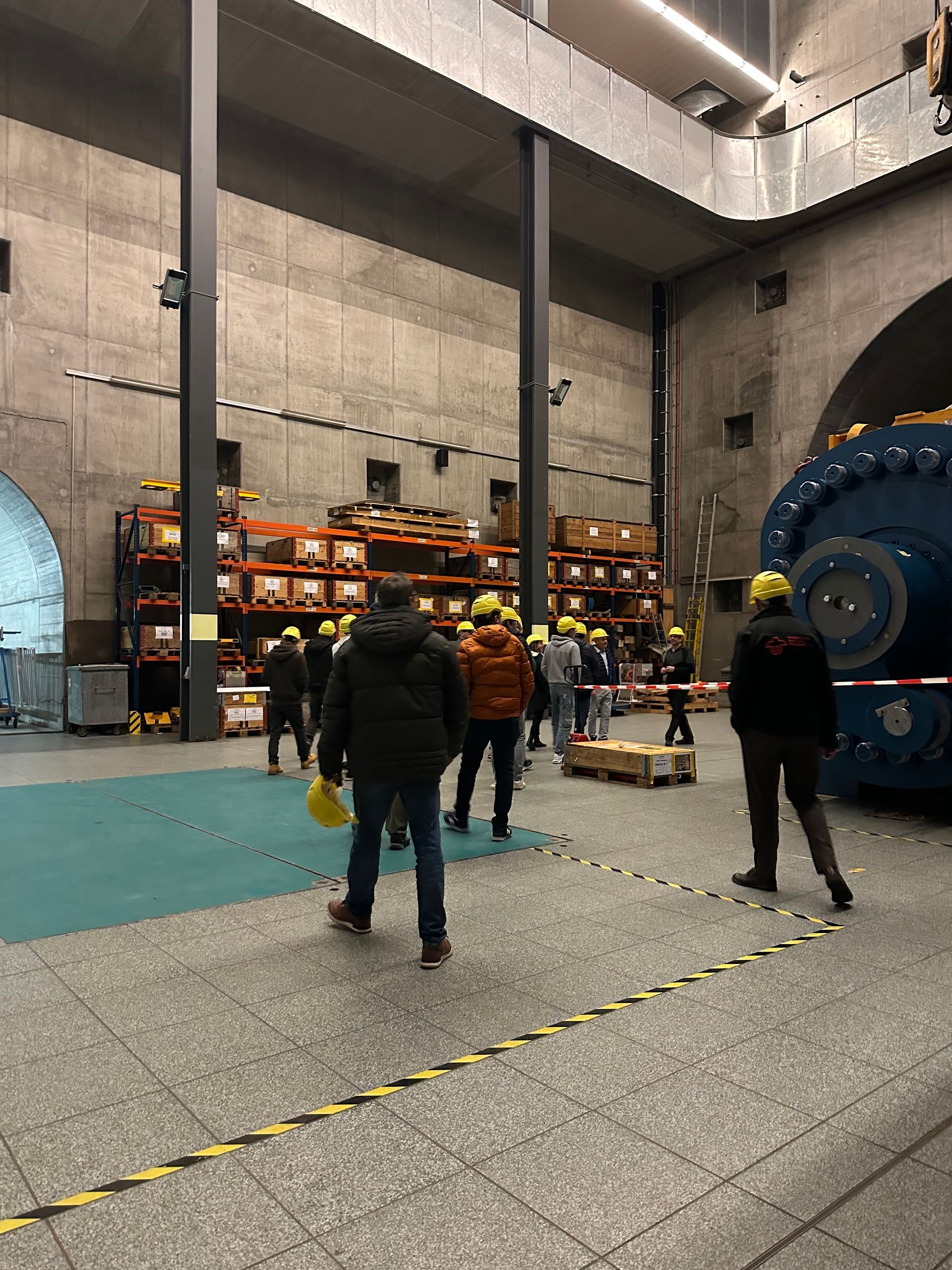 Un groupe de personnes se tient dans une grande pièce d'une usine.