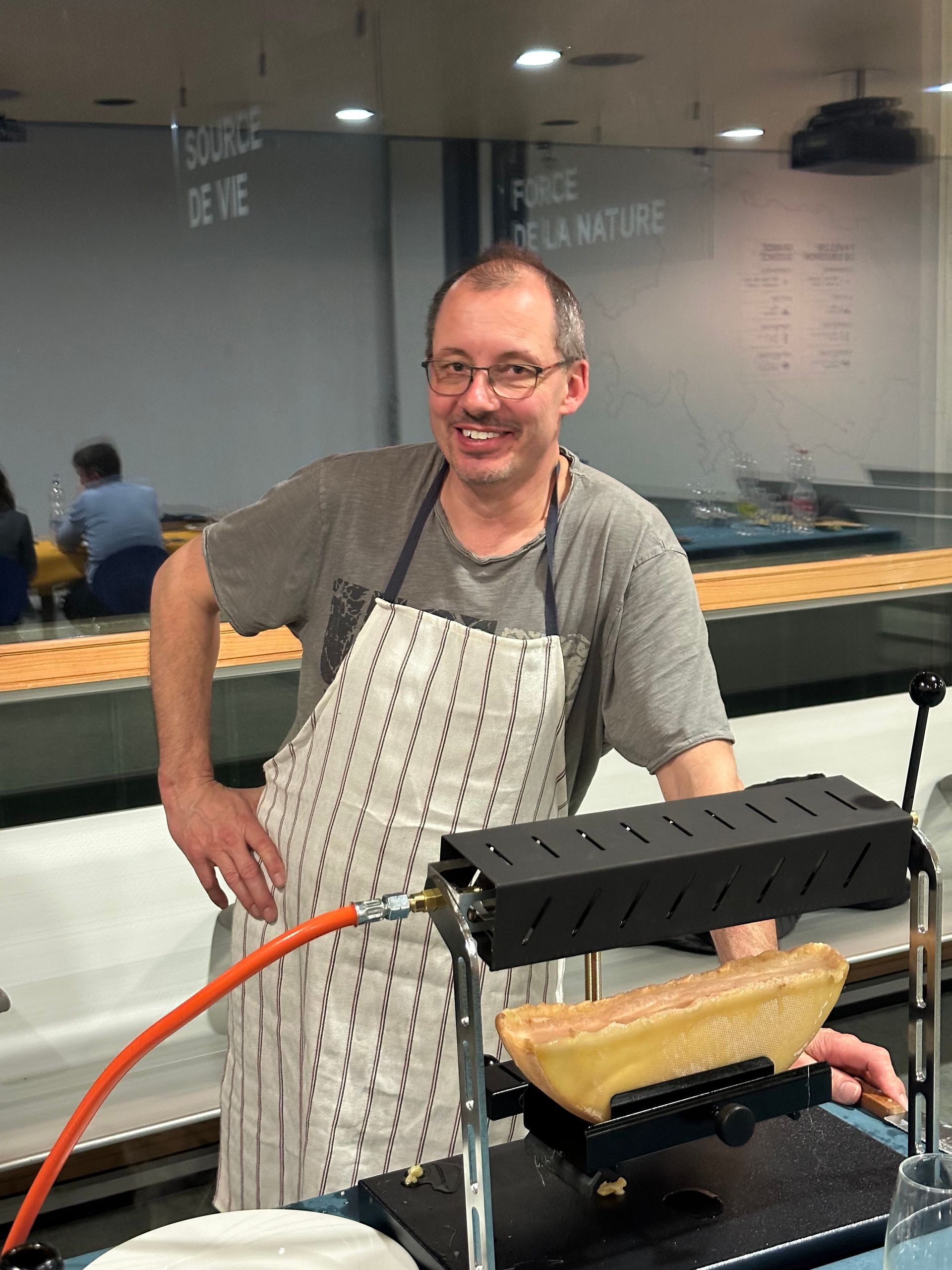 Un homme en tablier se tient devant un gril.