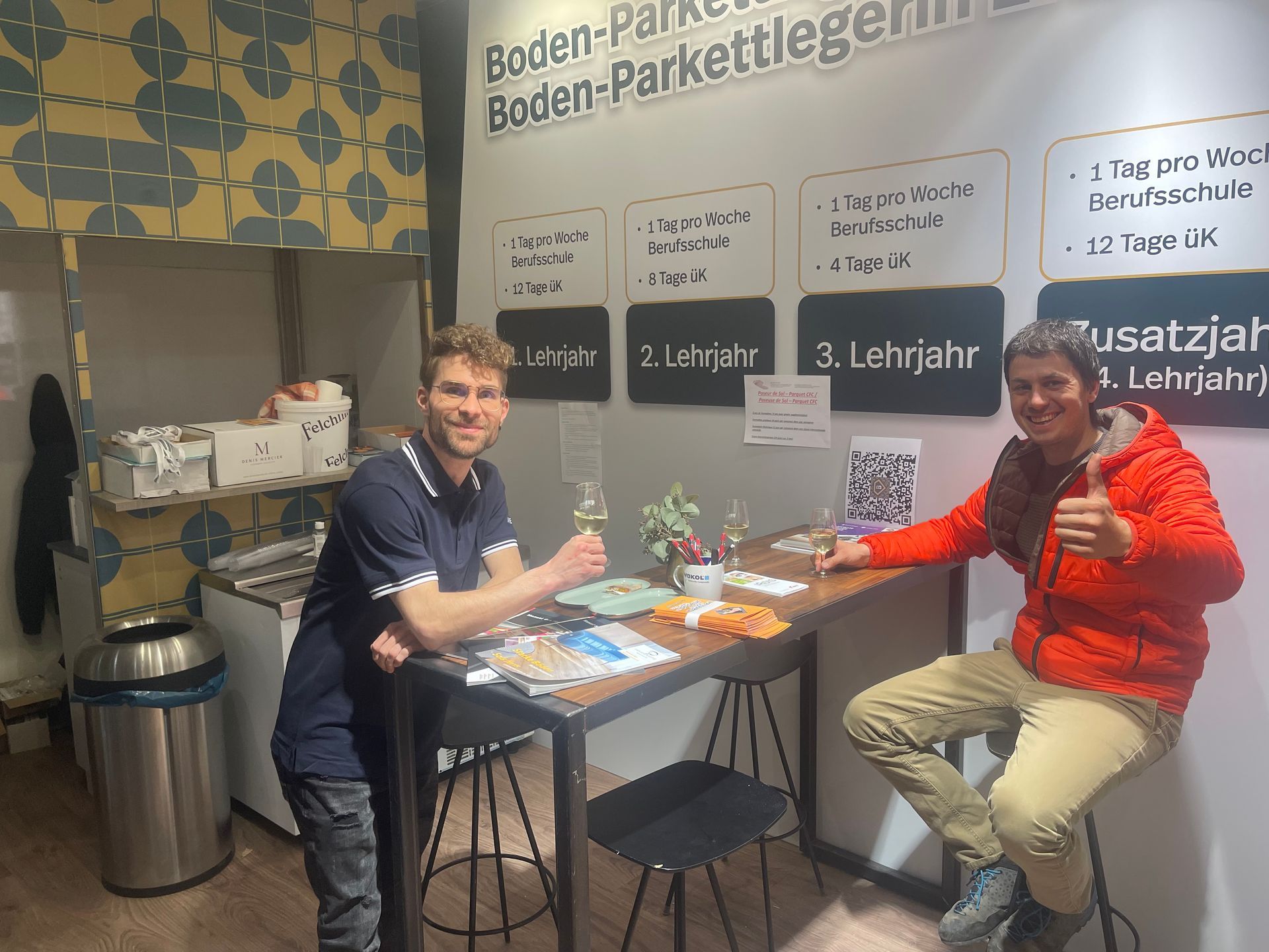 Deux hommes sont assis à une table et lèvent le pouce.