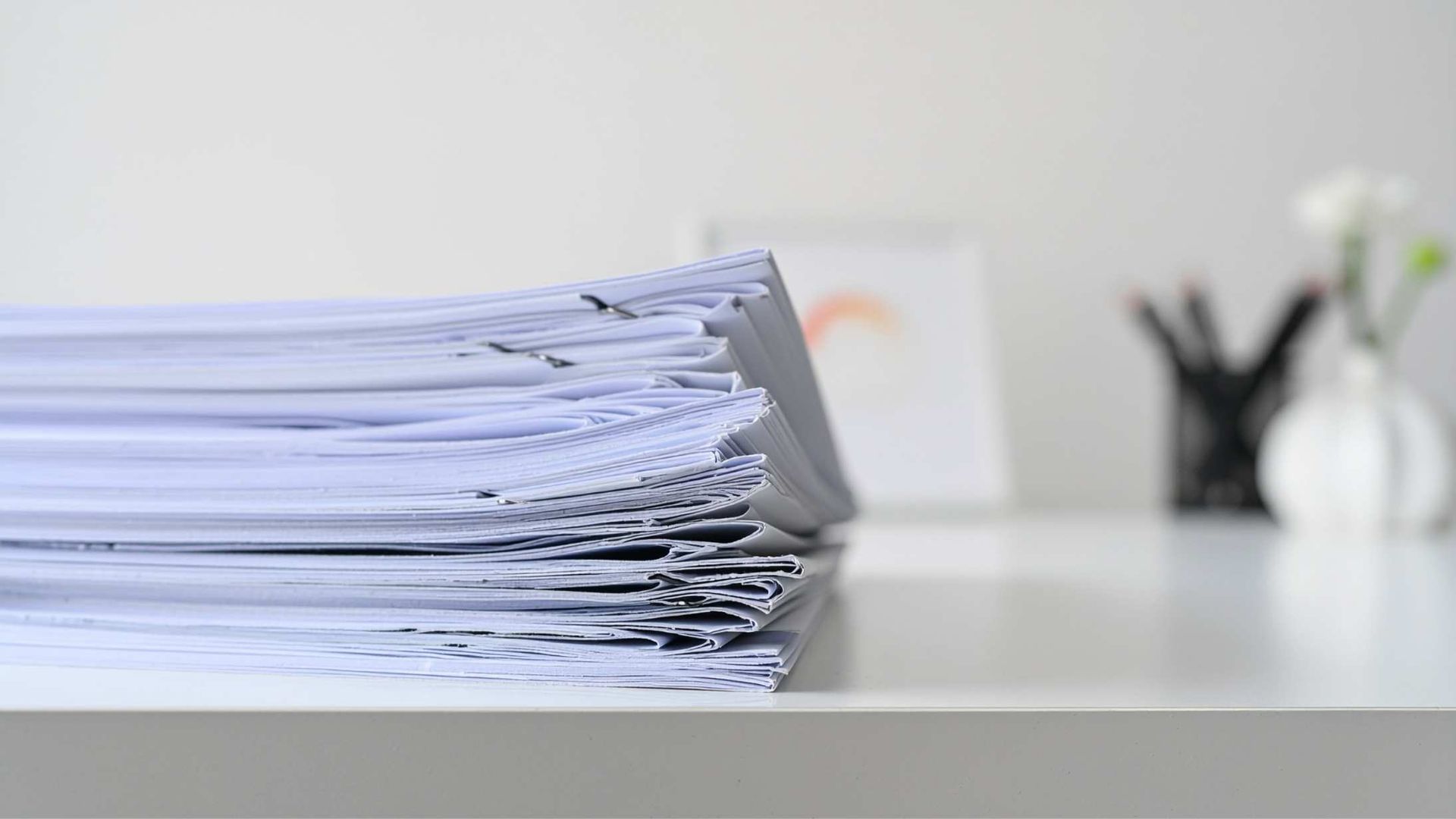 Stack of papers on a desk with a blurred office background