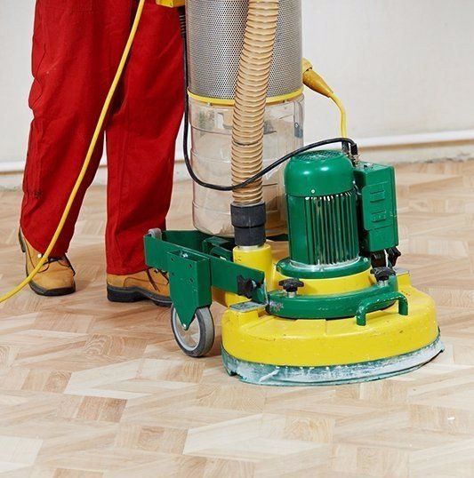 A person is sanding a wooden floor with a machine