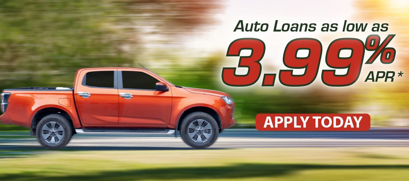 An orange pickup truck driving on a road, promoting auto loans as low as 3.99% APR with an 