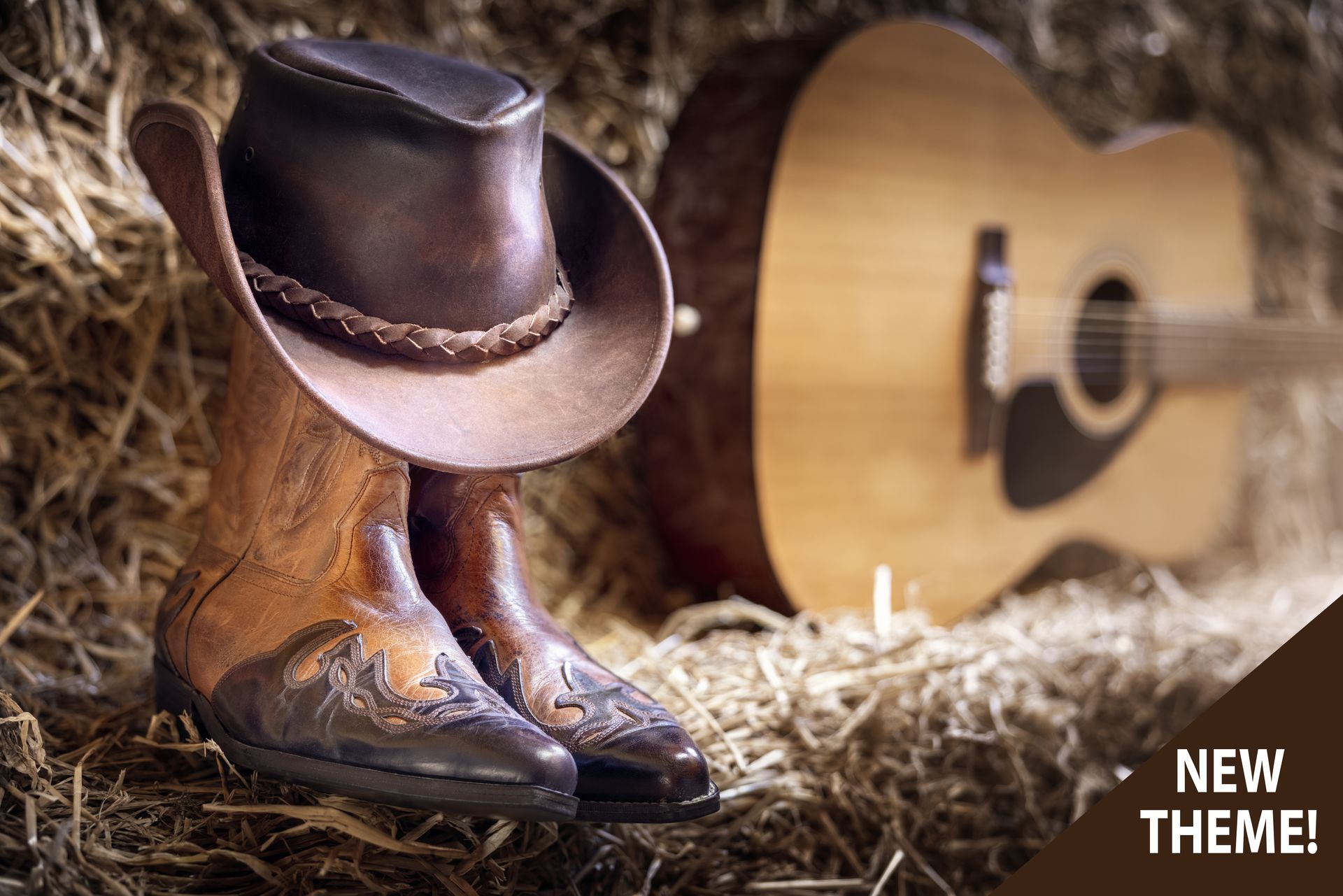 Cowboy boots with hat on a hay bale, guitar in background.