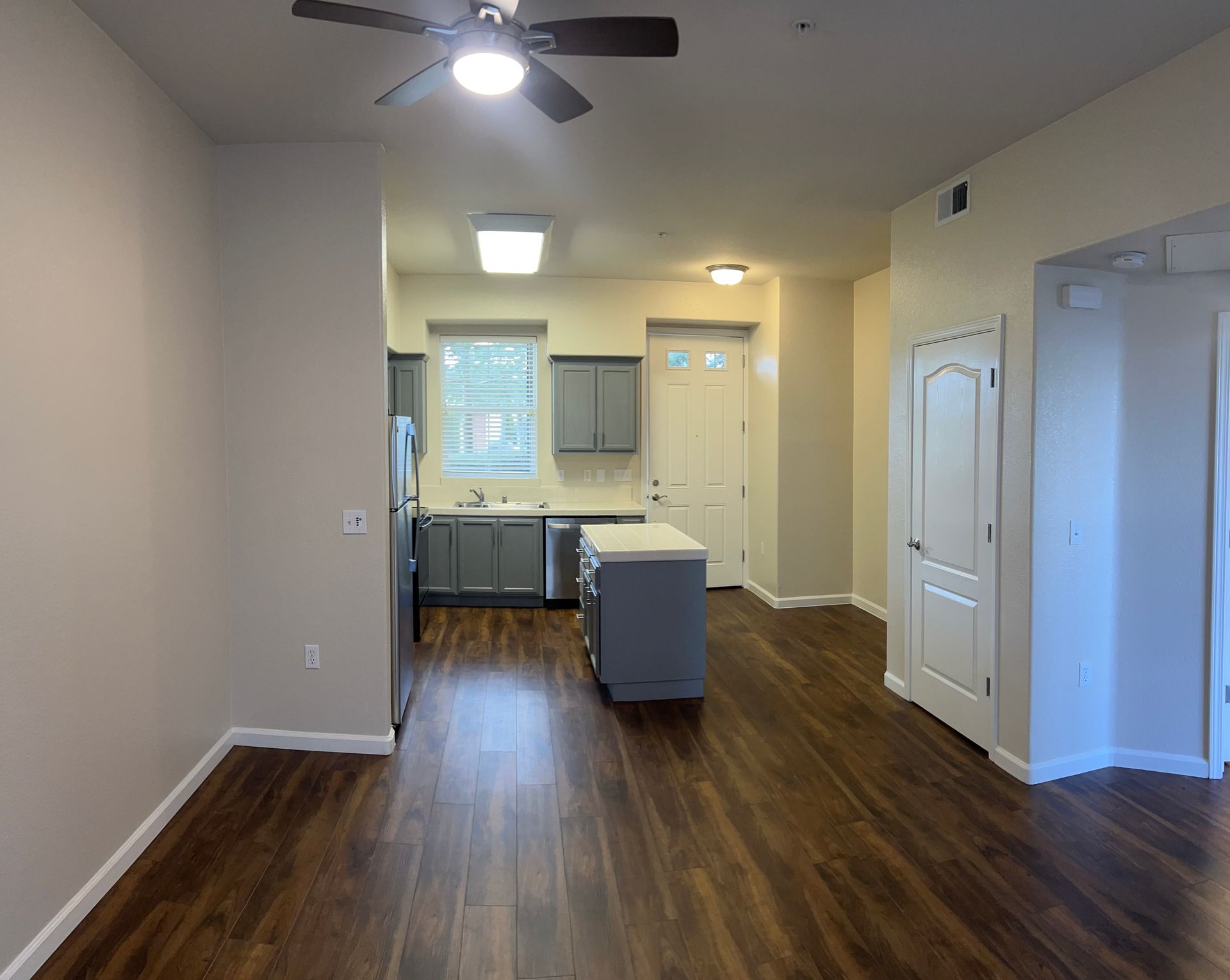 A living room with hardwood floors and a ceiling fan in an apartment.