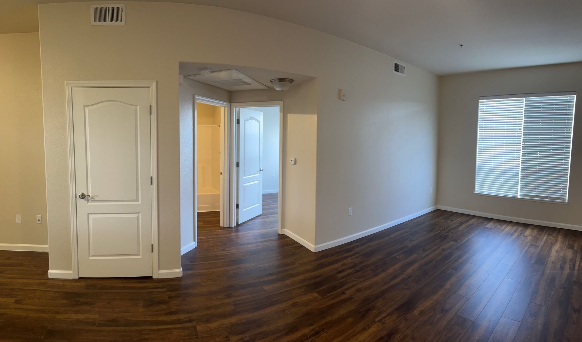 An empty living room with hardwood floors and white walls.