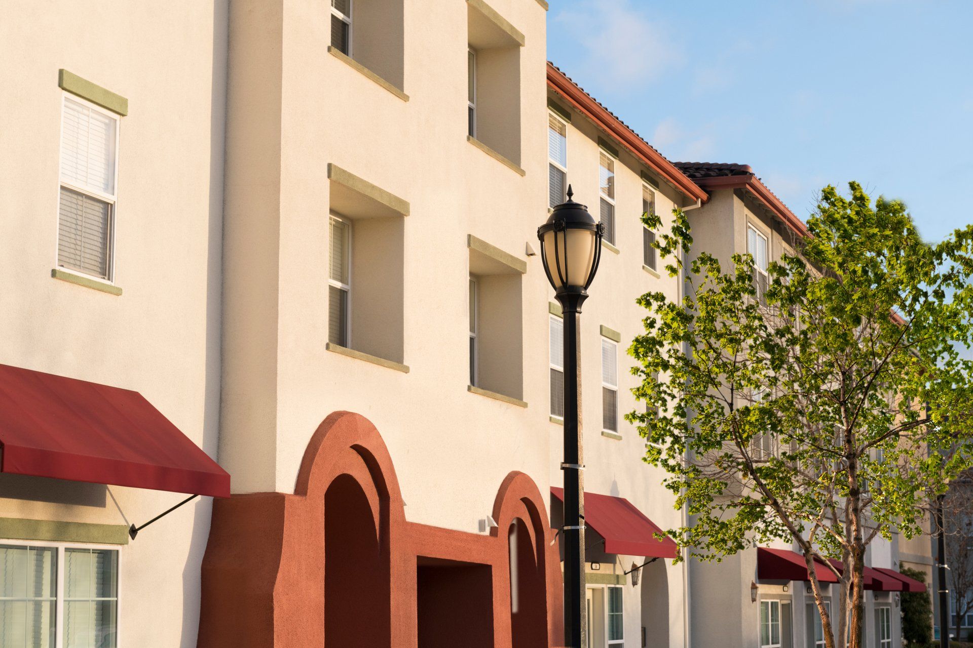 A row of apartment buildings with red awnings and a street light