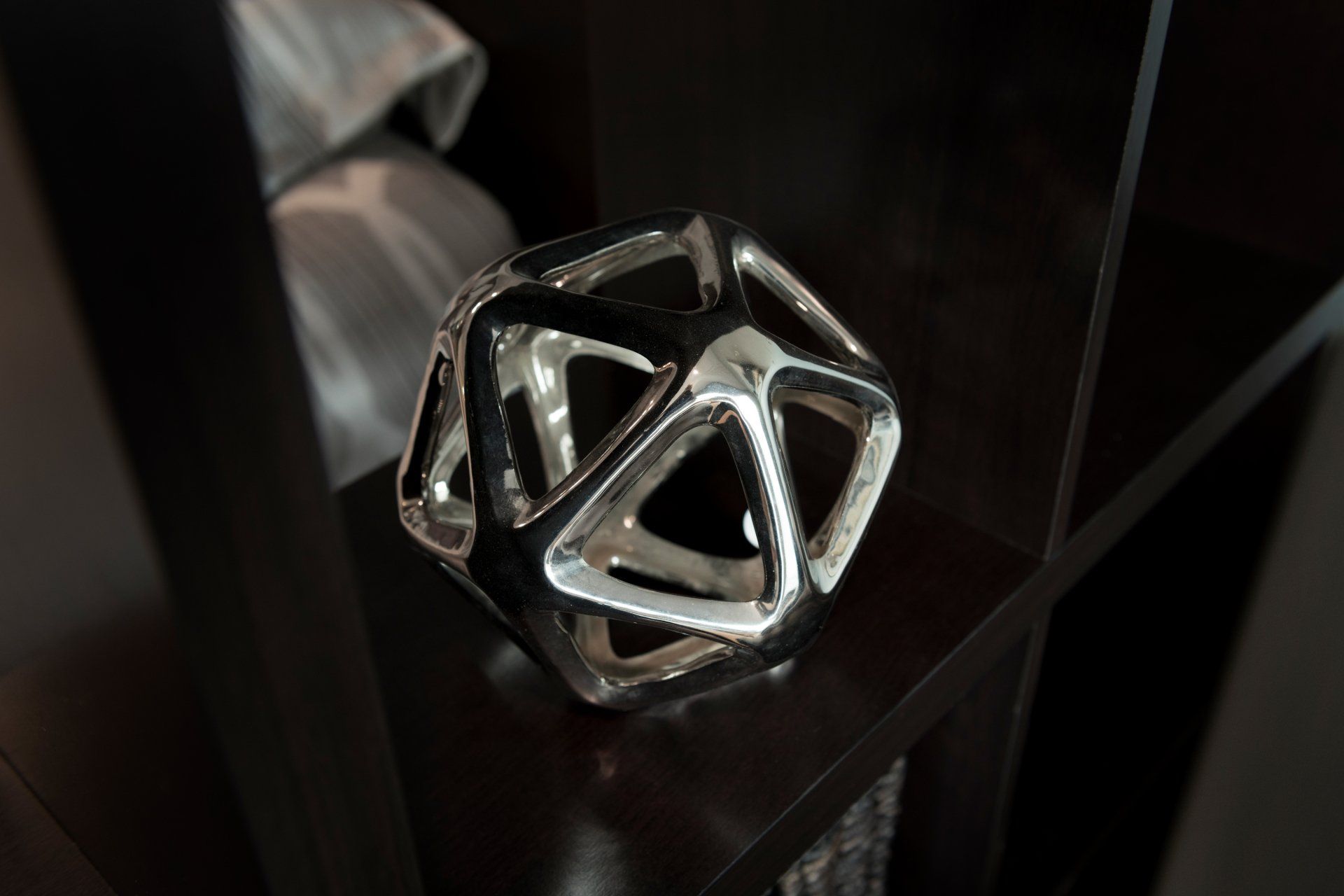 A silver object is sitting on a black shelf