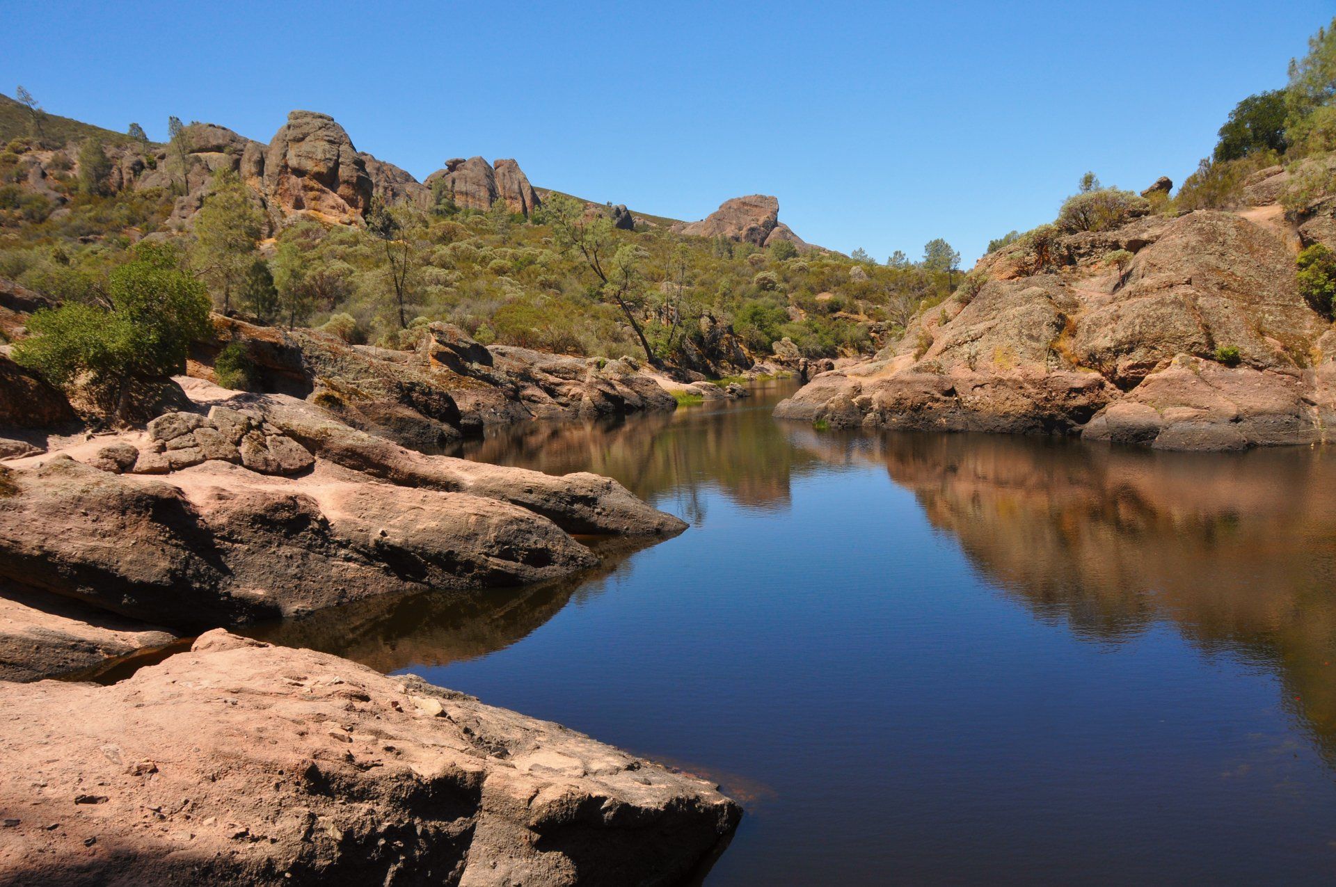 A lake surrounded by rocks and trees on a sunny day
