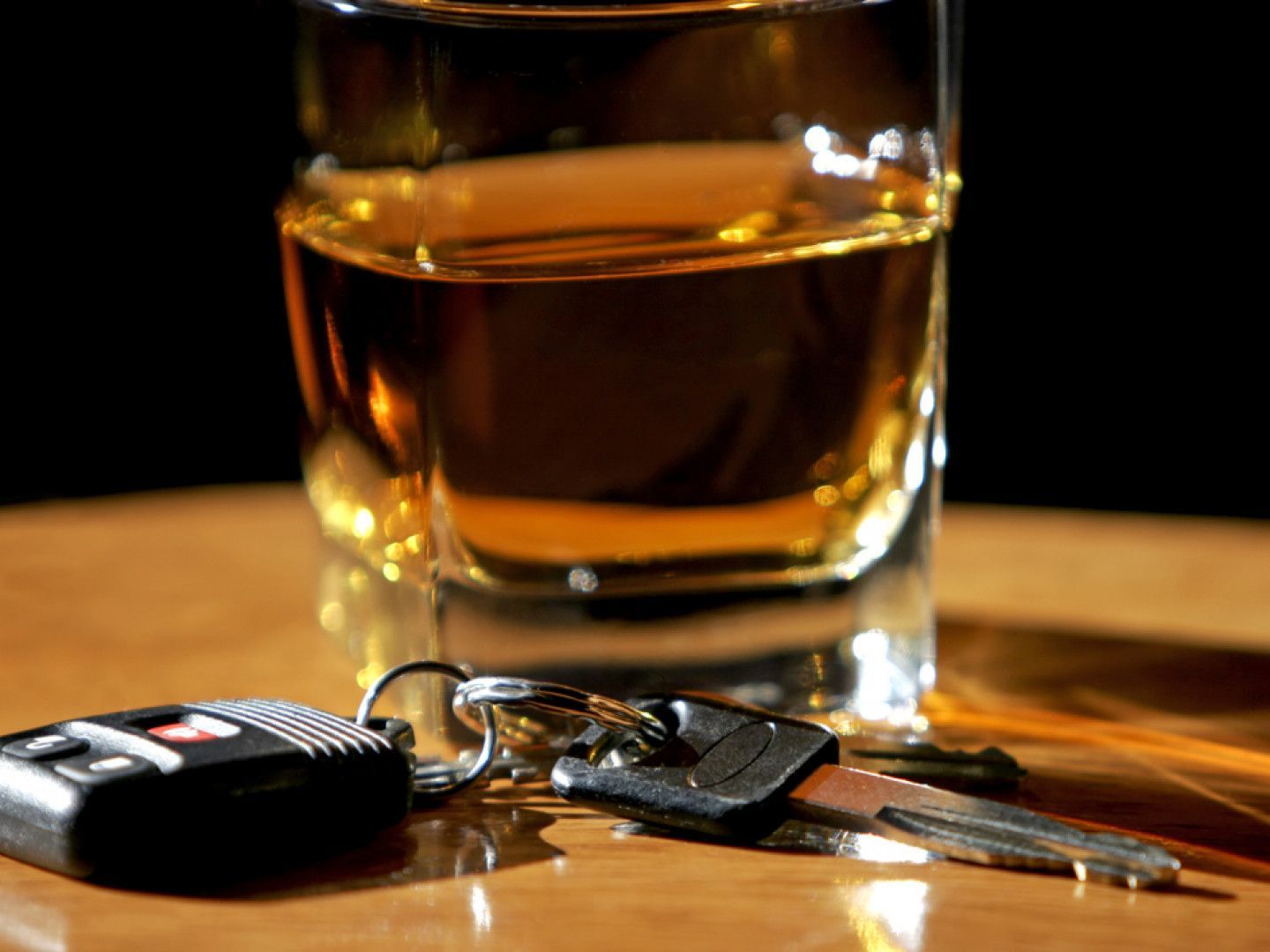 A glass of alcohol next to a car key on a table